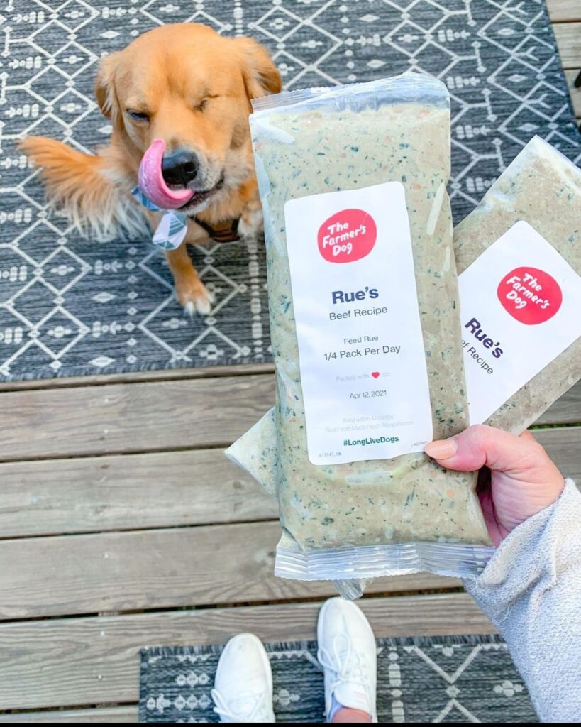 Golden retriever licking lips next to a pack of The Farmer's Dog beef recipe fresh food
